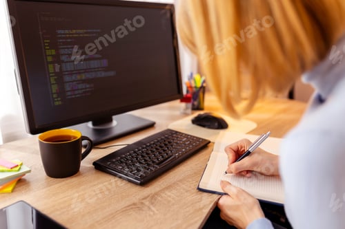 Preview: Woman taking online software engineering course writing in planner