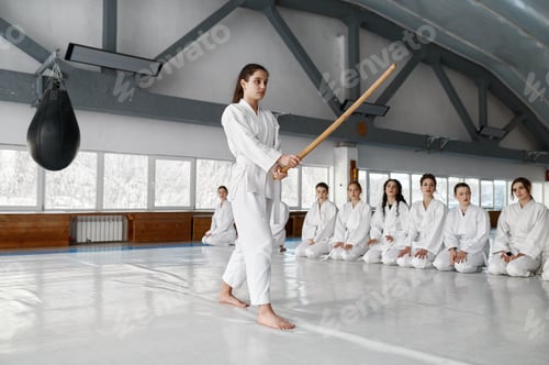 Preview: Young girl fighting with wooden sword at aikido training in martial arts school