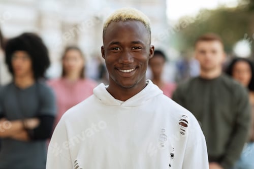 Preview: Cheerful young black guy standing over multiracial crowd
