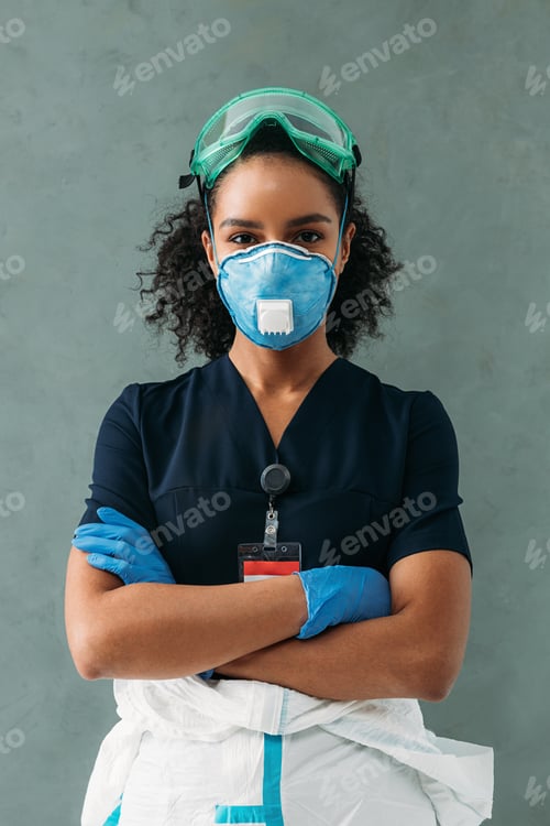 Preview: Portrait of a young nurse at wall. Female medical specialist standing with arms crossed.