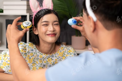 Preview: A young couple is designing and painting Easter eggs on Easter