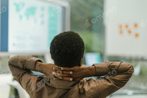 Preview: Businessman relaxing with hands behind head in office after work