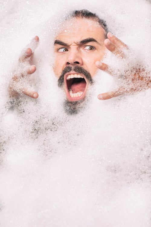 Preview: Man with moustache covered in bubbles pulling face