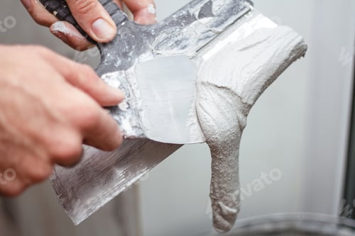 Preview: Man's hand removes excess plaster from the spatuia.