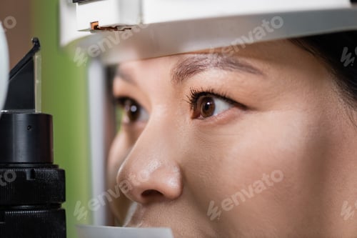 Preview: close up view of asian woman checking eyesight on blurred vision screener