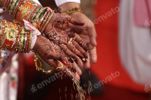 Preview: Closeup shot of a couple dropping grains on the floor under the lights during an Indian wedding