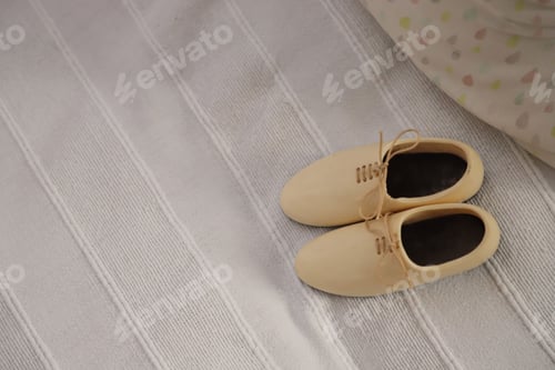 Preview: Closeup shot of a pair of white shoes on white blanket, with colorful material in the background