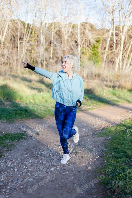 Preview: smiling sporty woman watching and pointing far away