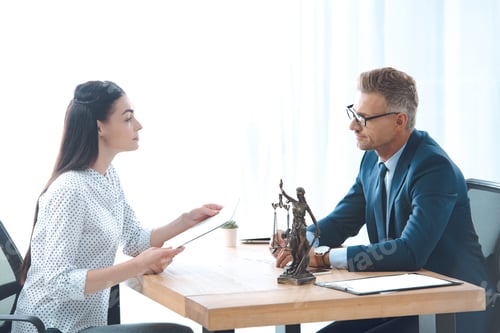 Preview: side view of lawyer and client discussing papers in office