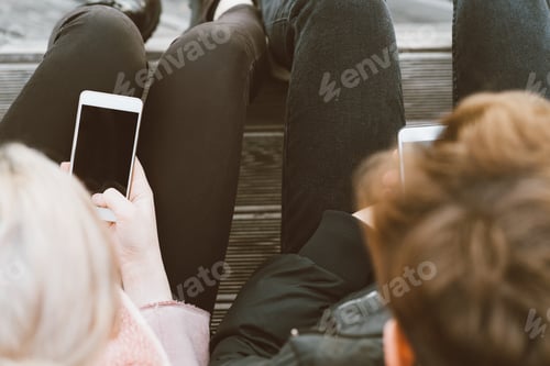 Preview: Loving teenagers on date look at mobile phones, sit on park bench in the fall
