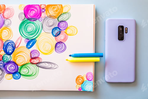 Preview: Top view of a modern blue mobile phone next to a drawing of colorful spirals with markers