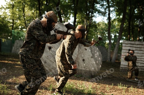 Preview: Team in uniform playing paintball in the forest