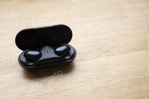 Preview: Top view of wireless earbuds on a wooden surface - copy space