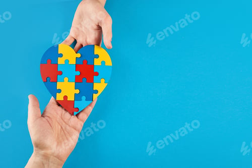 Preview: Father and autistic son hands holding jigsaw puzzle heart shape. World Autism Awareness Day