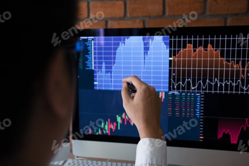Preview: Employees analyze the graph of the stock market using a pen pointing to the computer screen.