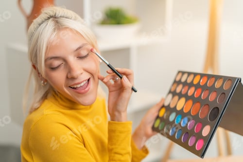 Preview: Smiling woman applying eyeshadow with a brush from a palette