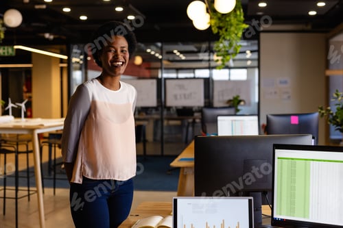 Preview: Mid-adult African American woman standing confidently in office with turbine models, copy space