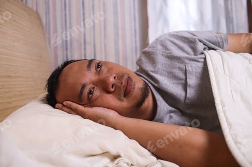 Preview: Man suffering insomnia lying on bed at bedroom