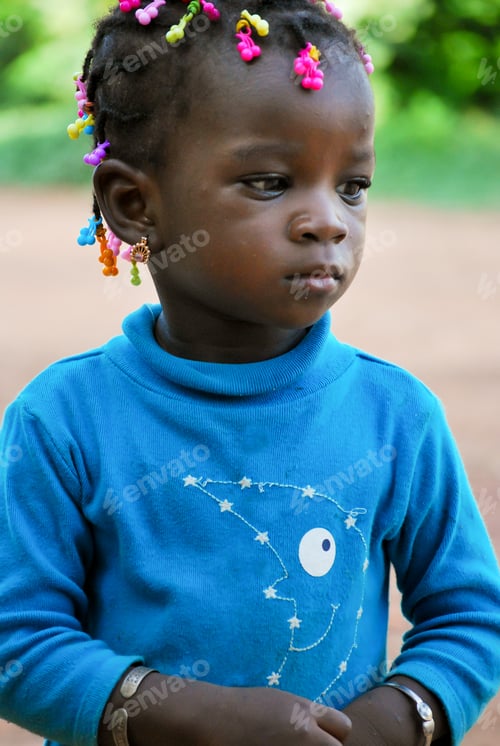 Preview: Little african girl with coloured pearls in her hair, looking straight into the camera