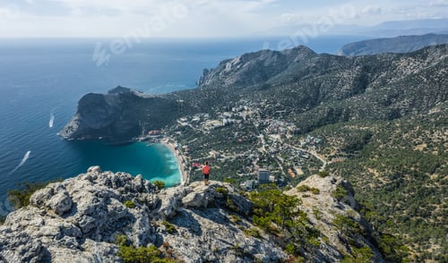 Preview: Man traveller at the top of Falcon Sokol mountain enjoying Novyi Svit town below. Crimea