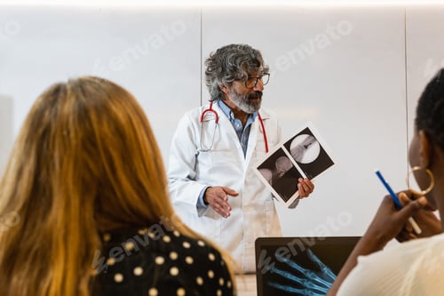 Preview: Senior doctor discussing x ray with colleagues in hospital