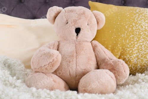 Preview: Cute teddy bear sitting on bed indoors