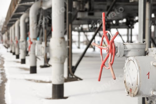Preview: The grey metal tubes for gas delivering with red valves at gas compressor station shooted in winter