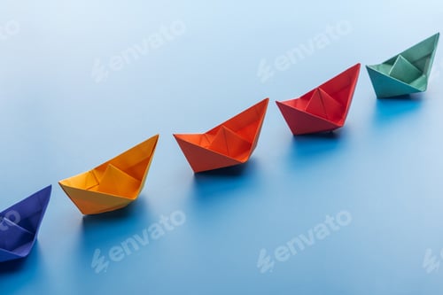 Preview: Colorful bright paper boats on light blue surface