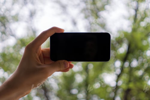 Preview: hand holding a black smartphone with copy space design mockup