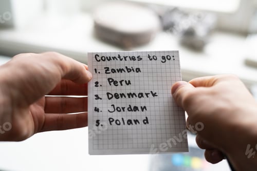 Preview: a person holding a paper note with countries to visit list