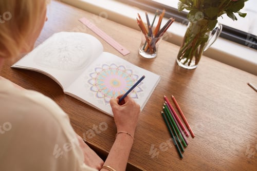 Preview: Woman drawing in colouring book for adults