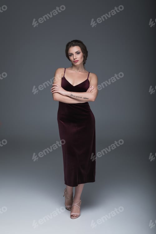 Preview: beautiful caucasian woman in evening dress looking at camera with arms crossed