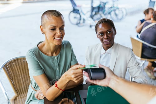 Preview: Woman paying with card at outdoor cafe