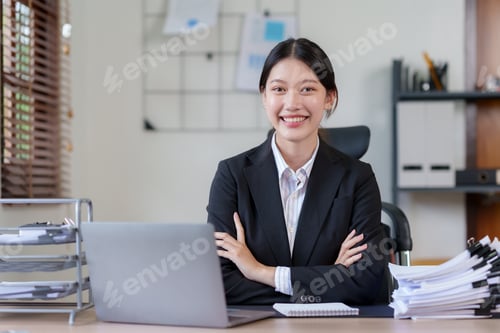 Preview: Beautiful Asian businesswoman sitting smiling, cross arms and opened her laptop and happily looking