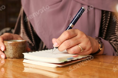 Preview: Close up of women hand writing on notepad.