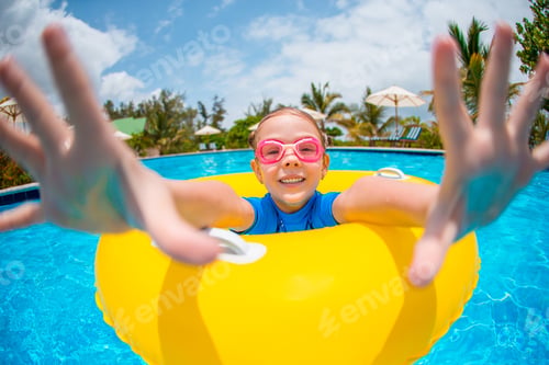 Preview: Happy kid with inflatable rubber circle having fun on the beach
