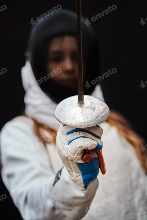 Preview: Portrait of woman dressed in fencing costume on black background.
