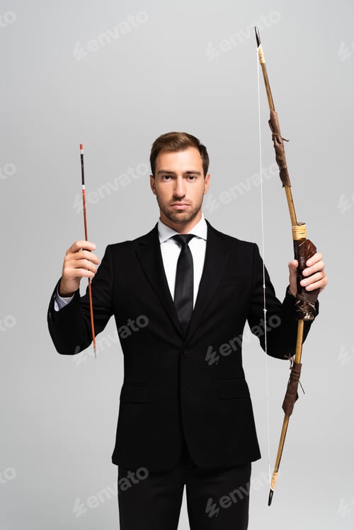 Preview: handsome businessman in suit holding bow and arrow isolated on grey