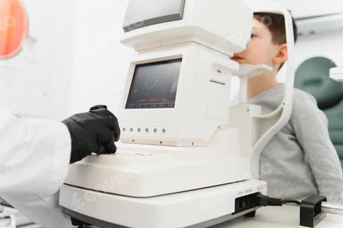Preview: Optometry concept. Female optometrist optician doctor examines eyesight of child boy