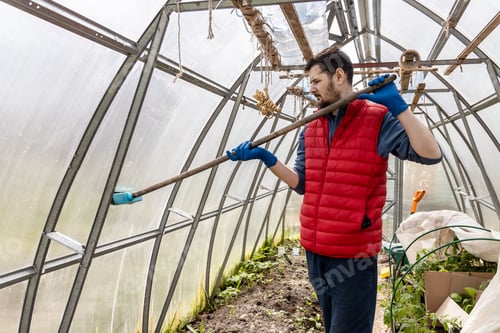 Preview: a man washes a greenhouse in the spring before planting seedlings