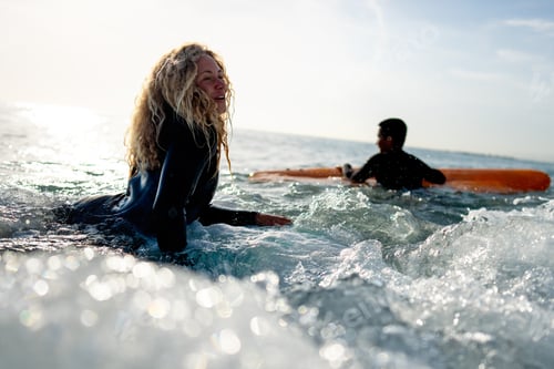 Preview: Fit couple surfing at sunset. Surfers friends having fun inside ocean. Sport and vacation concept