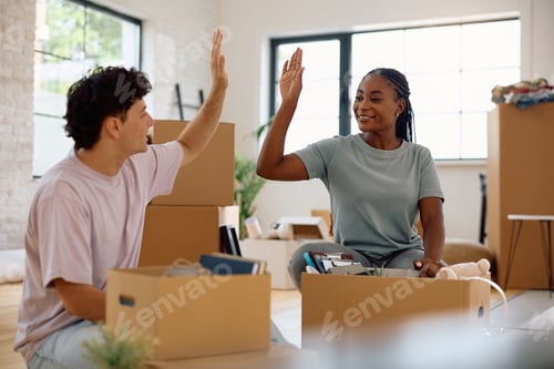 Preview: Happy couple of new homeowners giving high-five while unpacking their belongings.