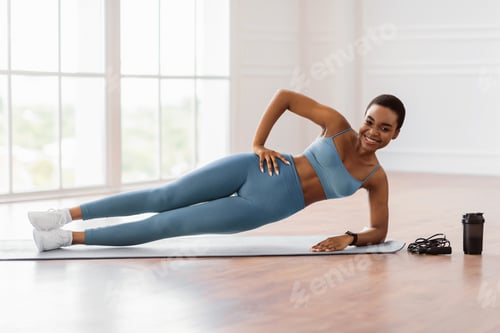 Preview: Young sporty woman doing side plank on mat