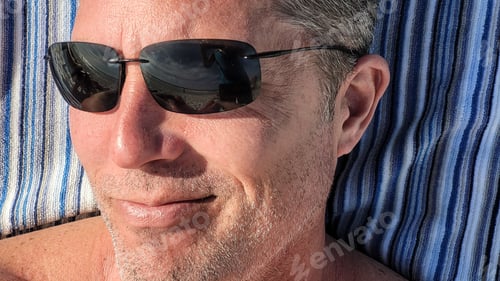 Preview: Millennial in shades found on the shoreline of beach on vacation being cool on a sunny day.