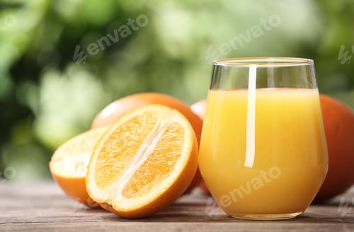 Preview: Glass of fresh juice and oranges on wooden table. Space for text