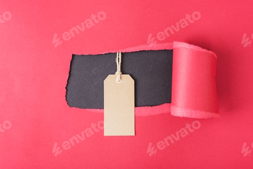 Preview: Kraft paper tag on red torn paper background. Black friday, Christmas sale concept. Top view,