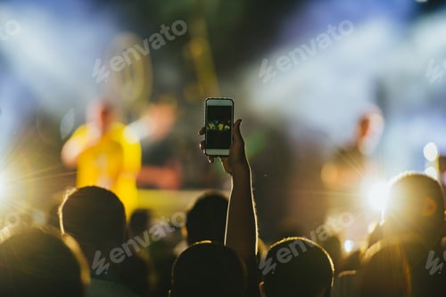Preview: Man hand taking picture in a concert on a music festival