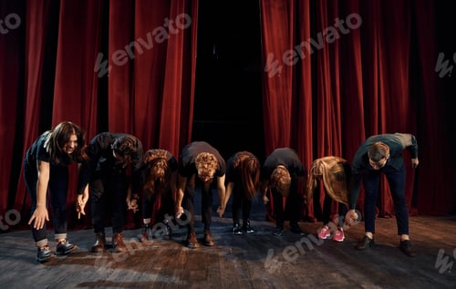 Preview: People bowing to audience. Group of actors in dark colored clothes on rehearsal in the theater