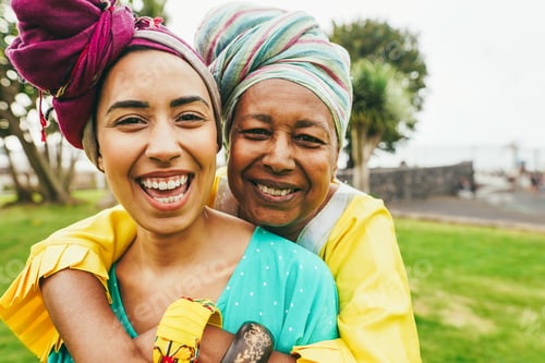 Preview: Happy african mother and daughter wearing traditional clothes while having fun together outdoor