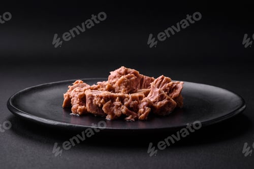 Preview: Delicious canned tuna meat on a black ceramic plate on a dark concrete background
